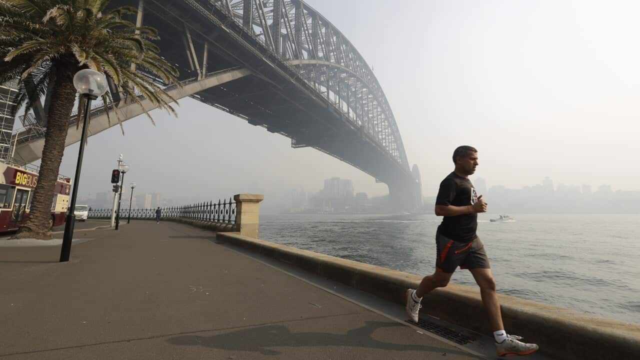 A man jogs under the Sydney Harbour Bridge as a smoke haze hangs over the famous landmark.