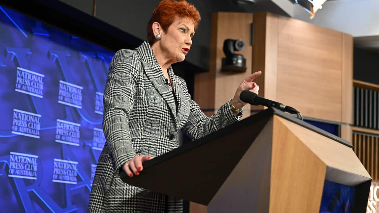 Pauline Hanson delivers her speech in a check coat with trademark red hair