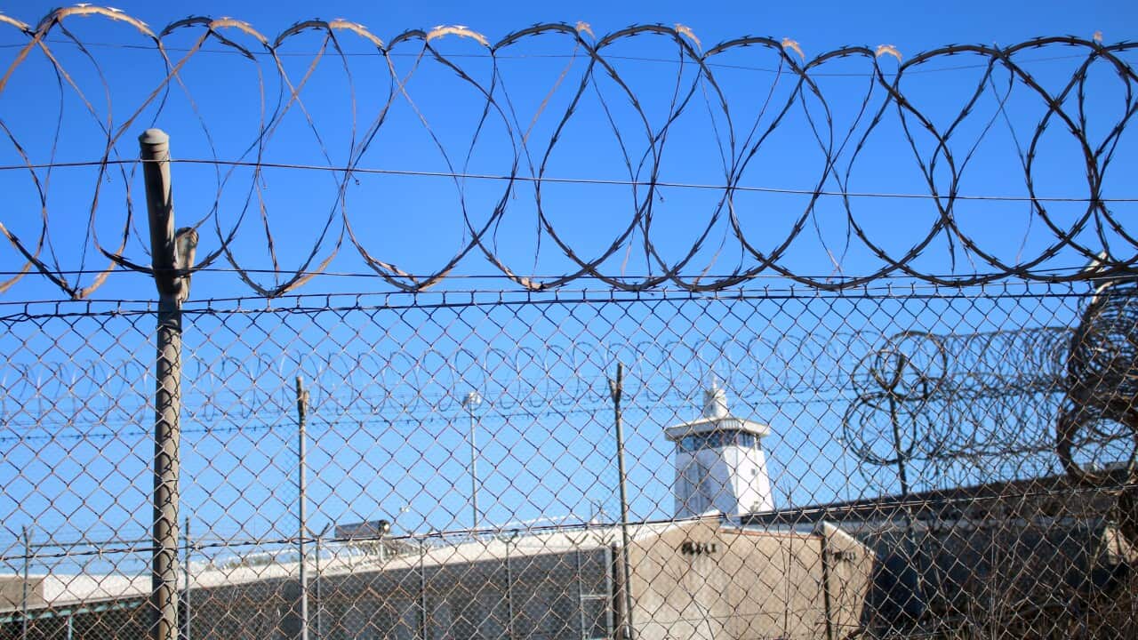 A barbed wire fence in front of a watch tower.