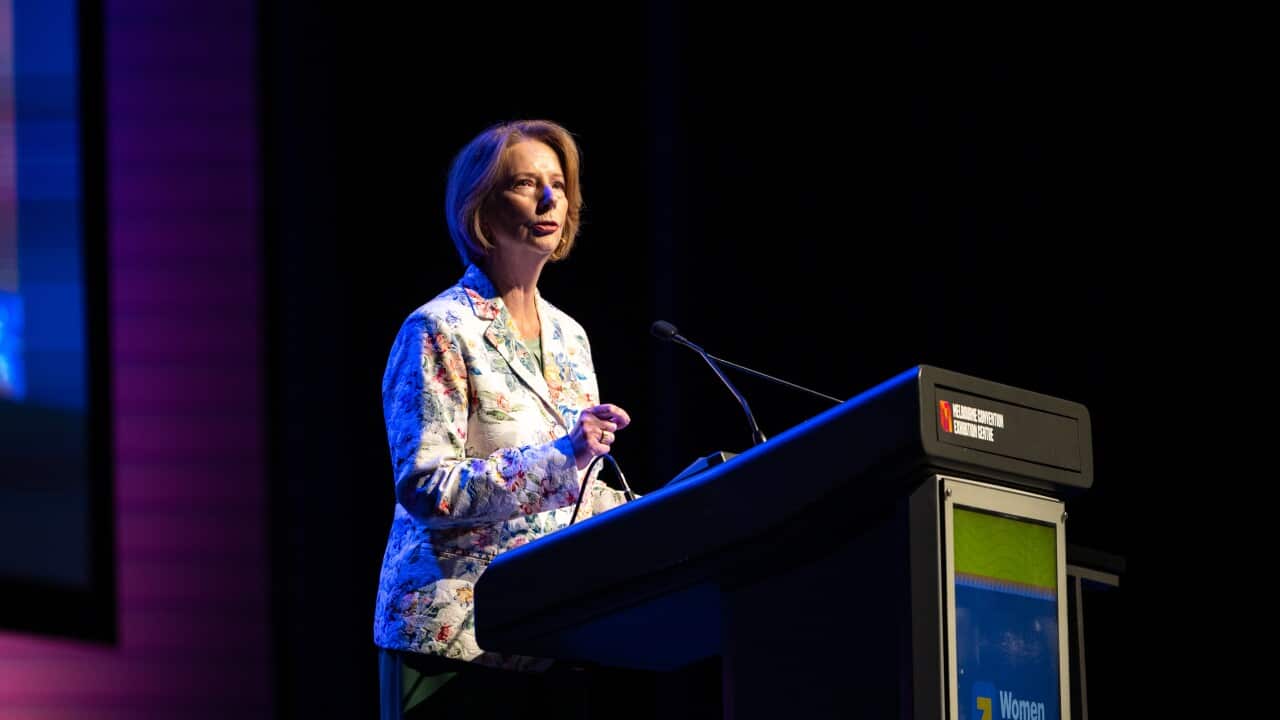Julia Gillard stands behind a lecturn