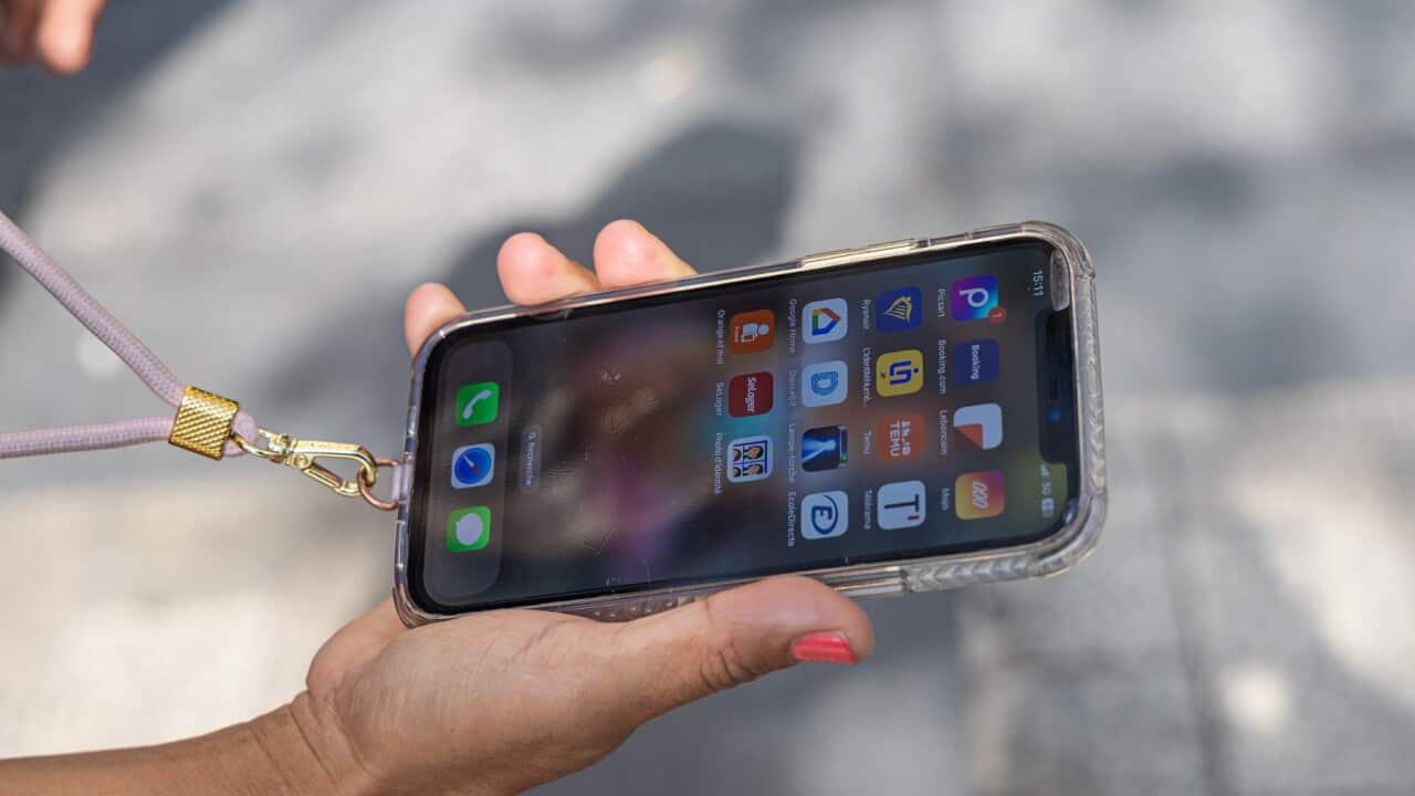 A customer shows her iPhone 12 in front of the Apple Store on the Champs Elysees Avenue in Paris, France (AAP).