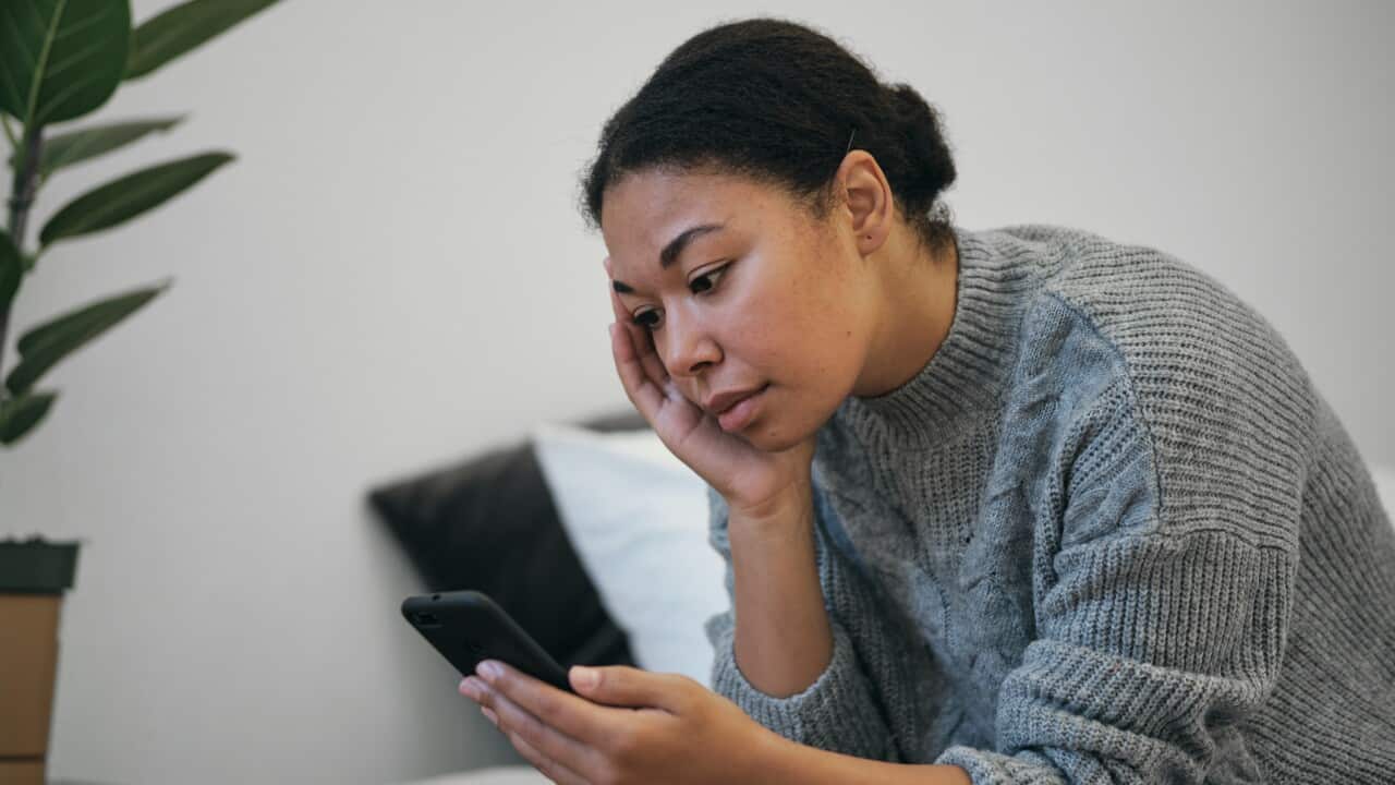 A woman looking stressed reading her phone