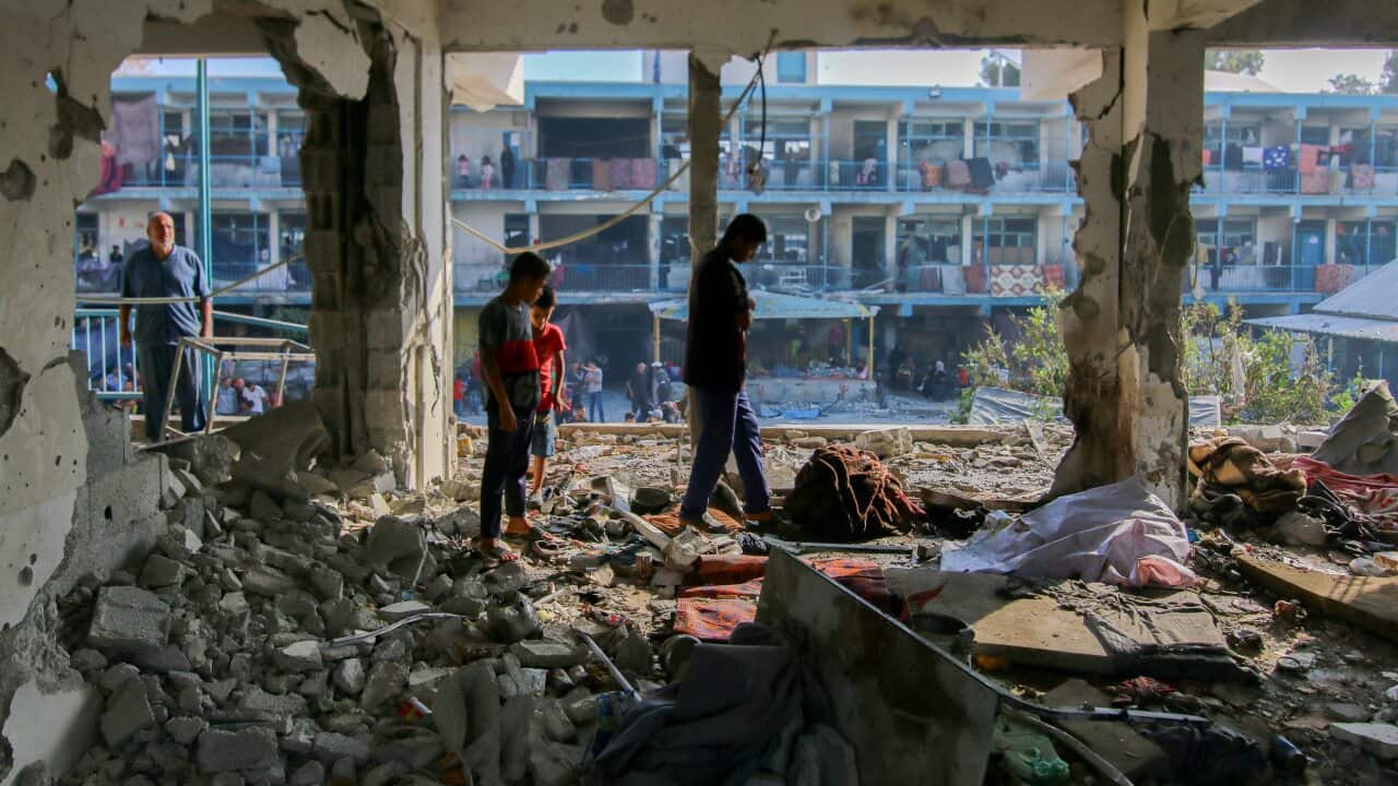 Children standing in the rubble of a destroyed building.