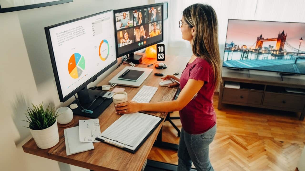 Woman at standing desk home office talking on business video call