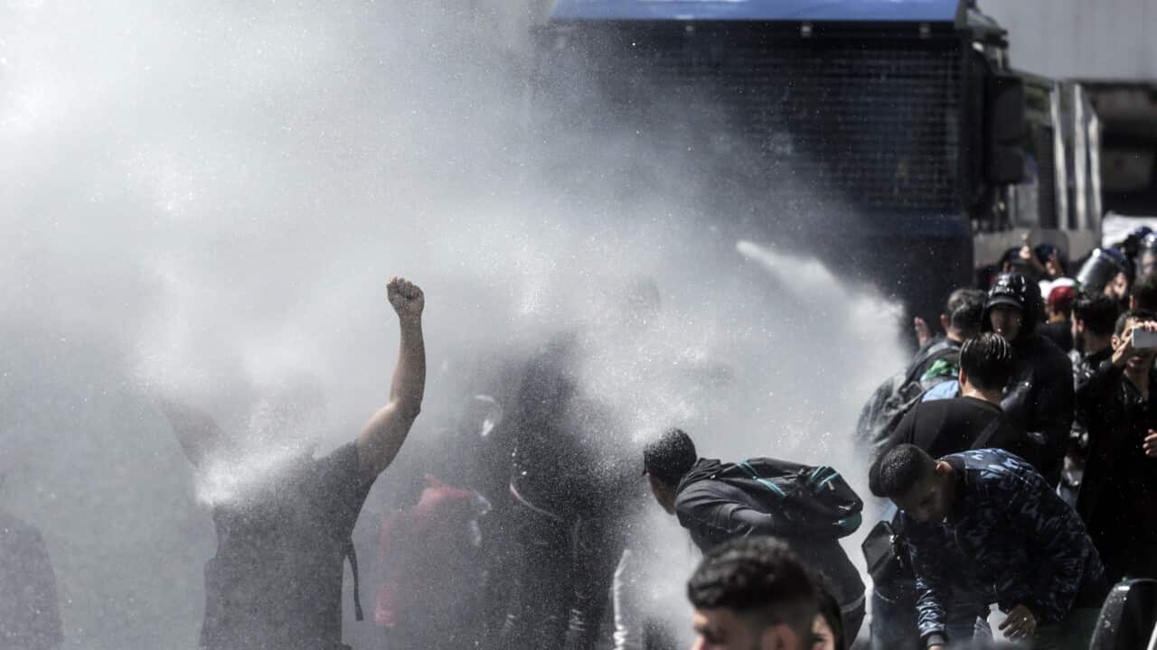 A protester gestures as he is sprayed with a water cannon during a demonstration for students in Algiers, Algeria.