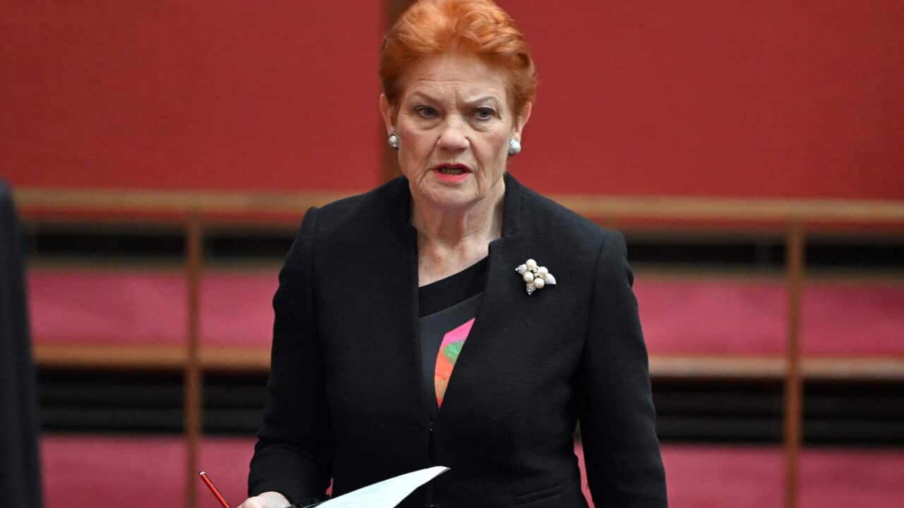 A woman wearing a black suit looks on
