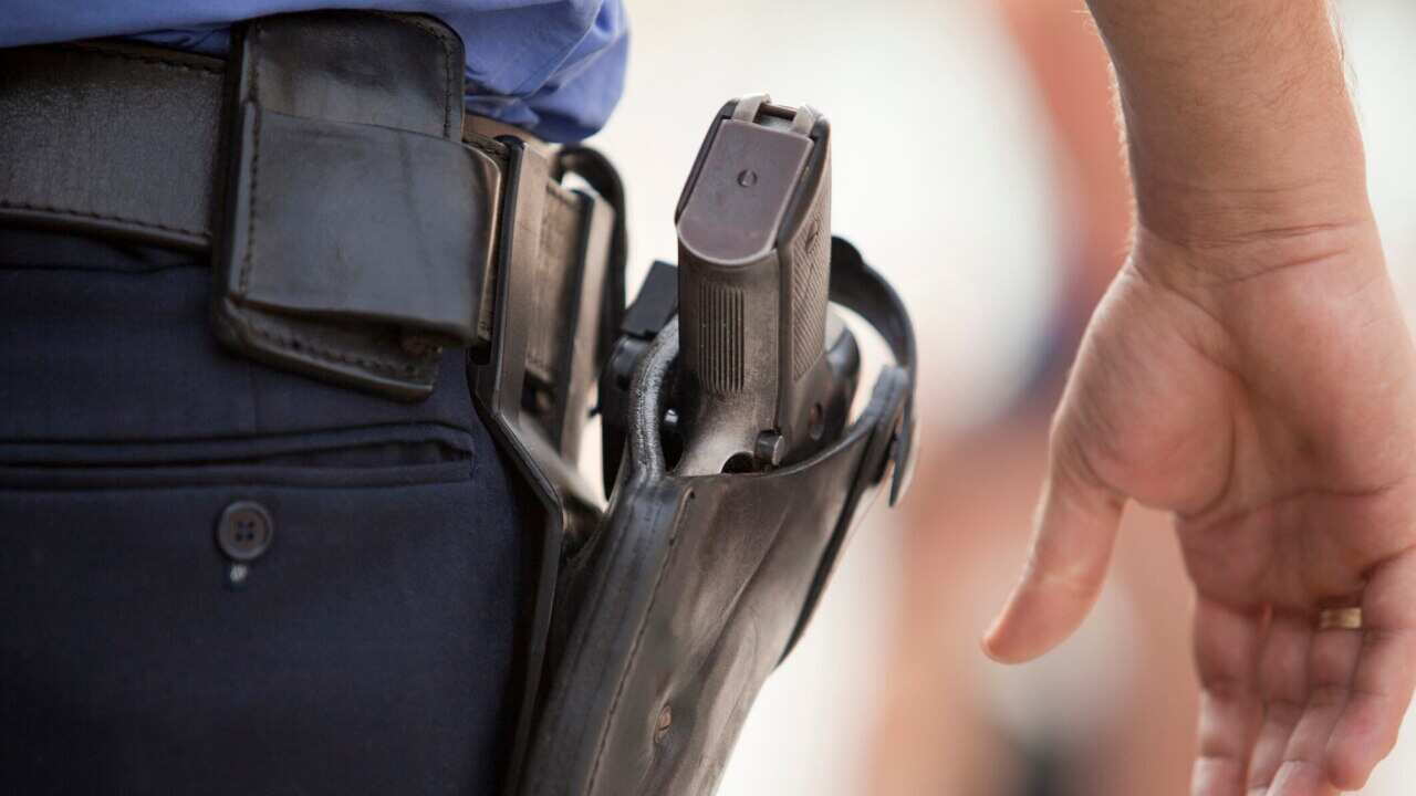 A policeman with his hand close to his gun.