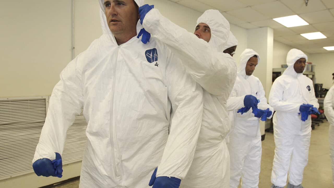 Soldiers practice putting on protective clothing and gloves in Texas.