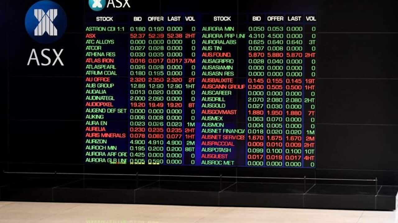 Man looking at mobile phone near ASX board.