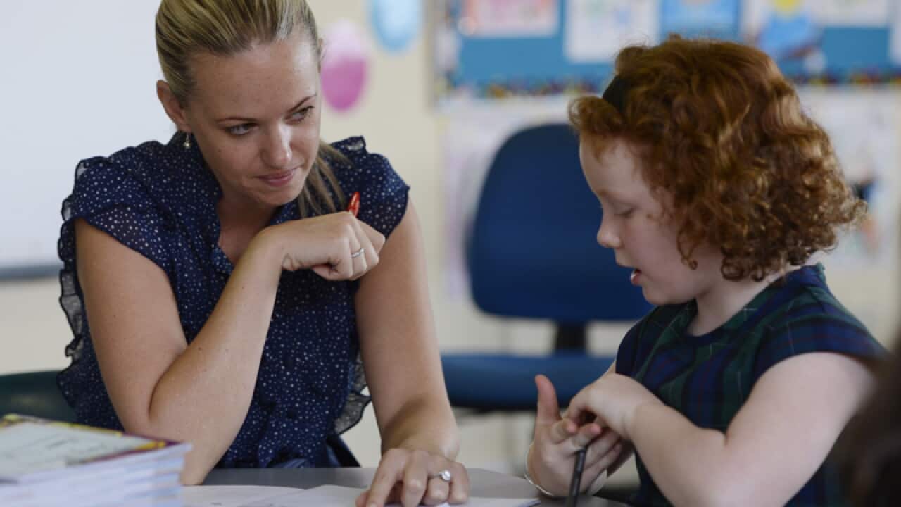 A teacher speaks with a student at a primary school