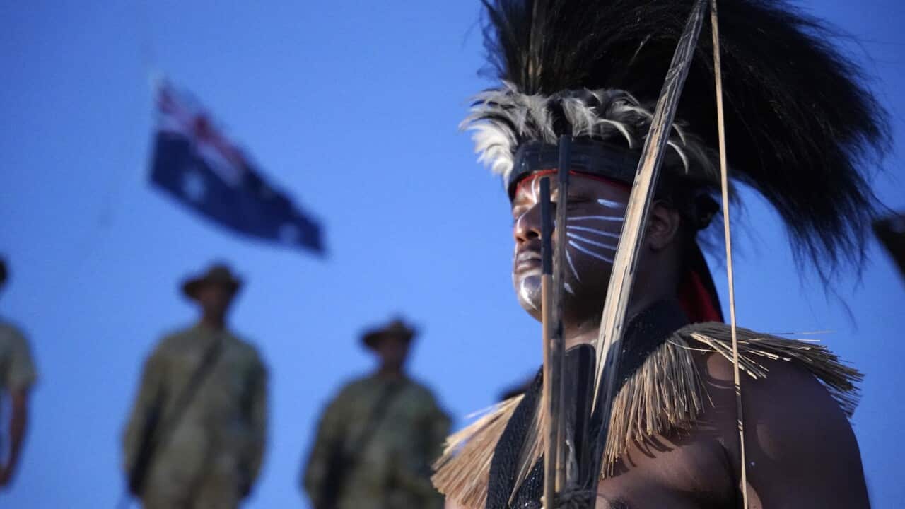 A person wearing traditional clothing and face paint at a dawn service ceremony.