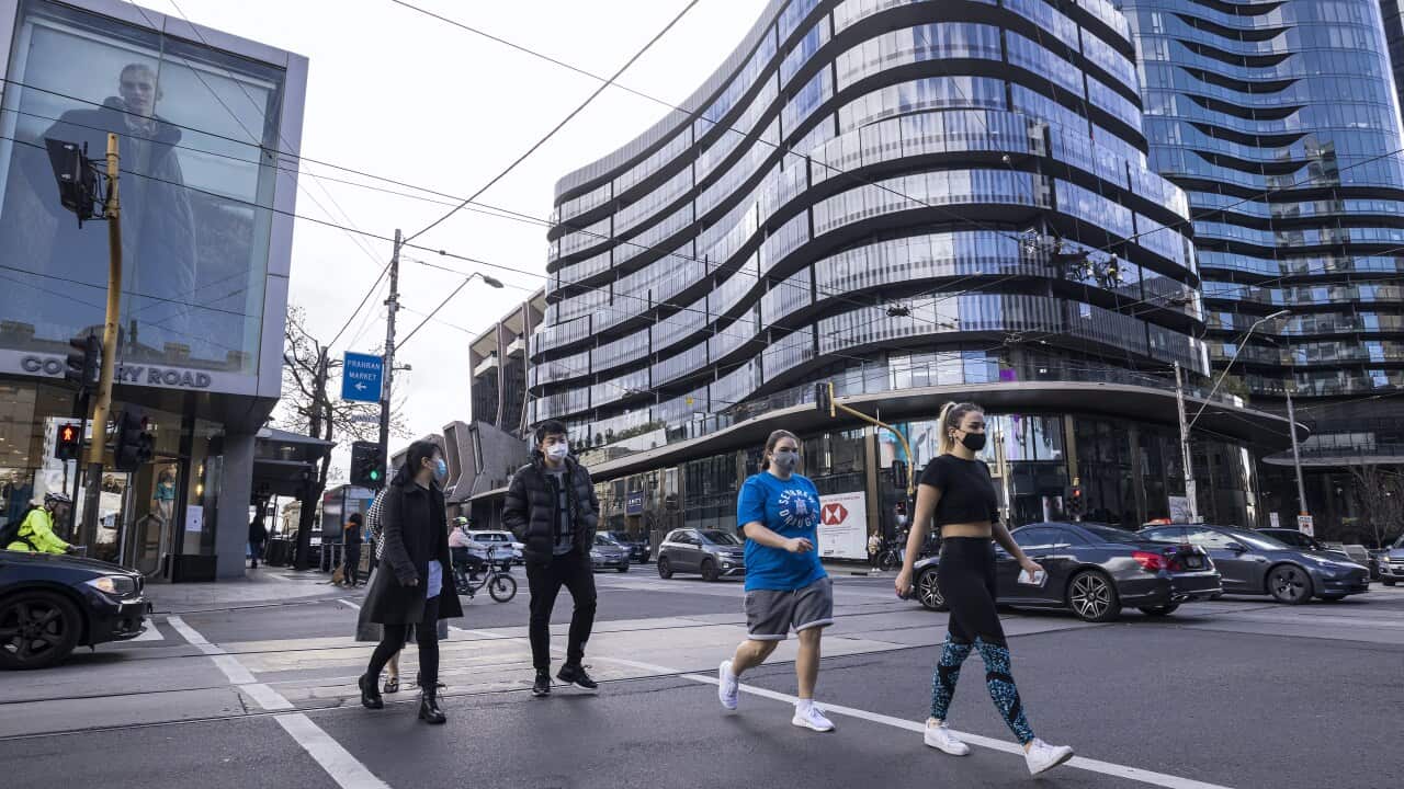 People are seen crossing a road in South Yarra, Melbourne.