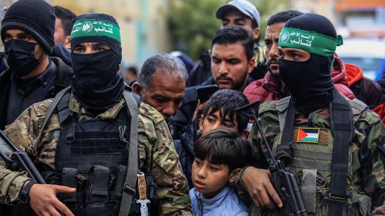 Members of Hamas in military uniforms standing among civilians.