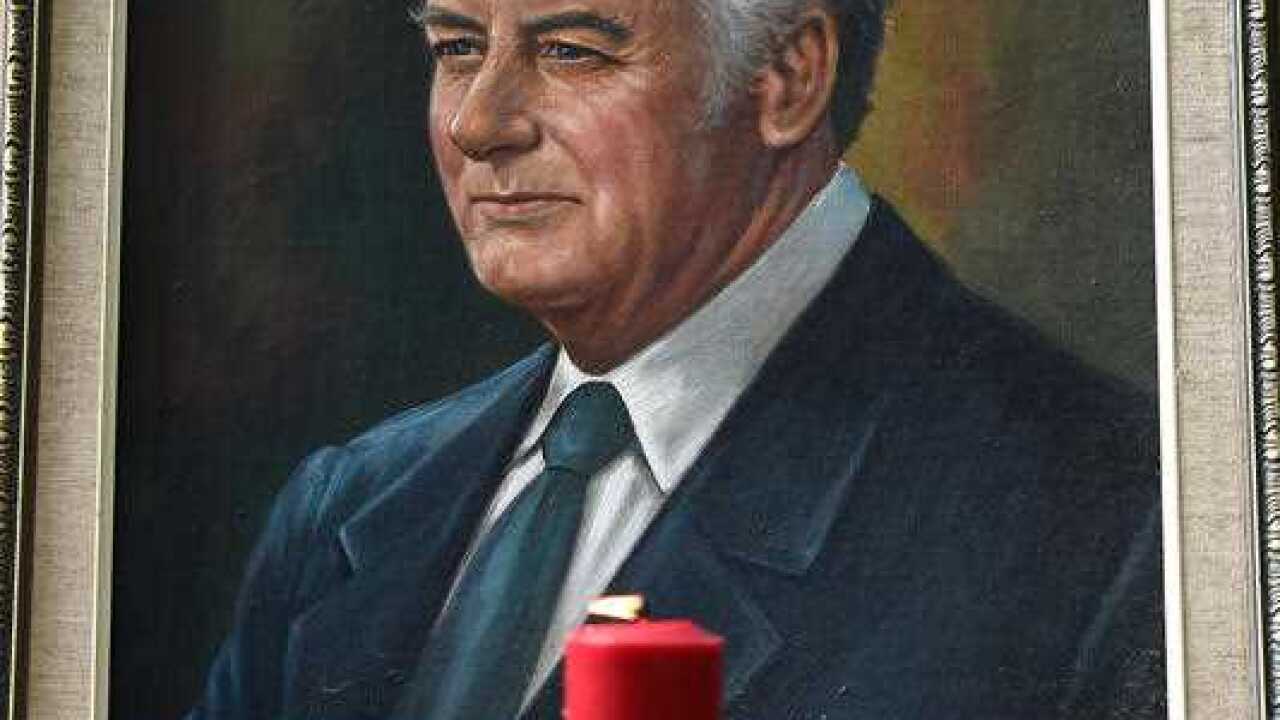 A portrait of Gough Whitlam with a candle sits across from the memorial service for the former Prime Minister outside of the Town Hall in Sydney