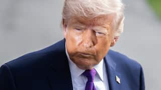 Donald Trump, wearing a blue blazer, white shirt and purple and blue tie.