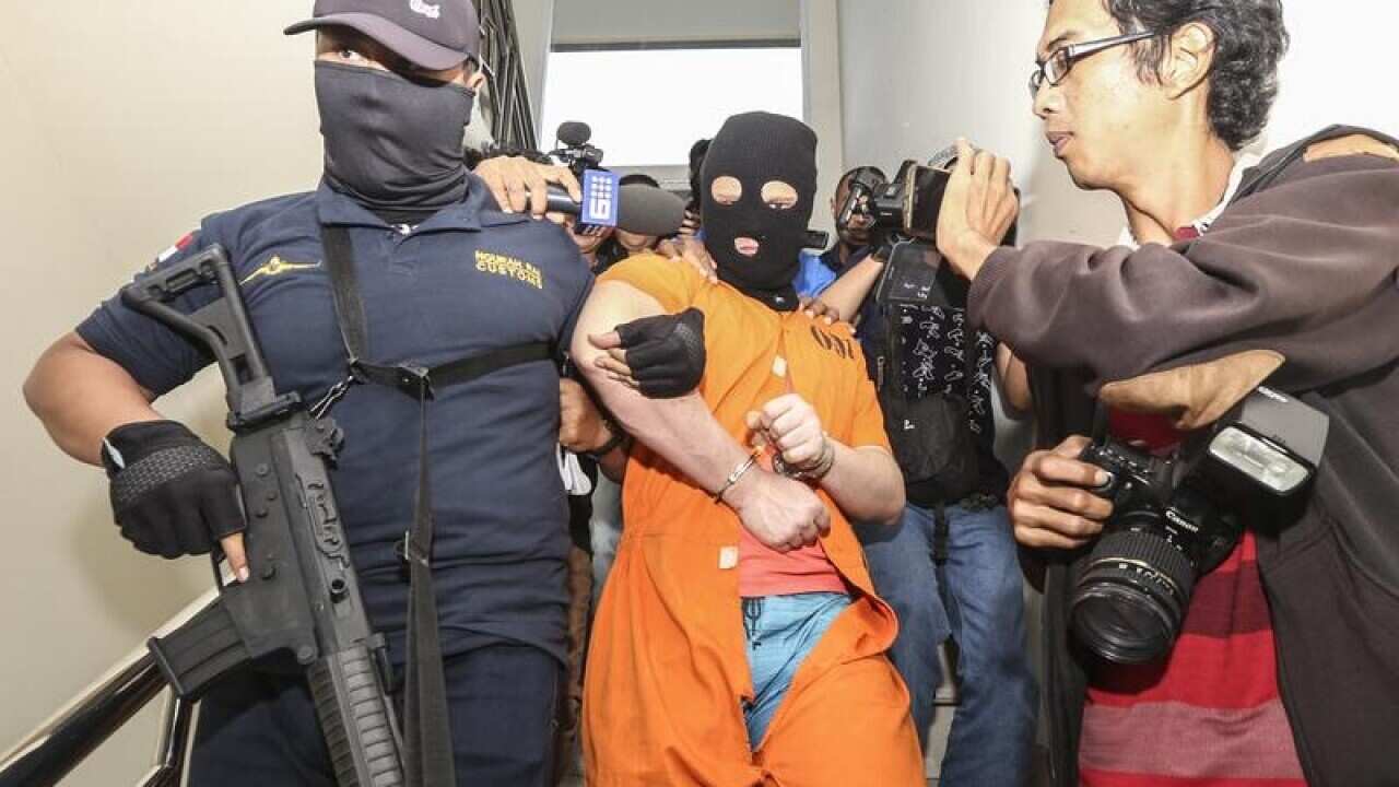 An Australian man is escorted by officers.