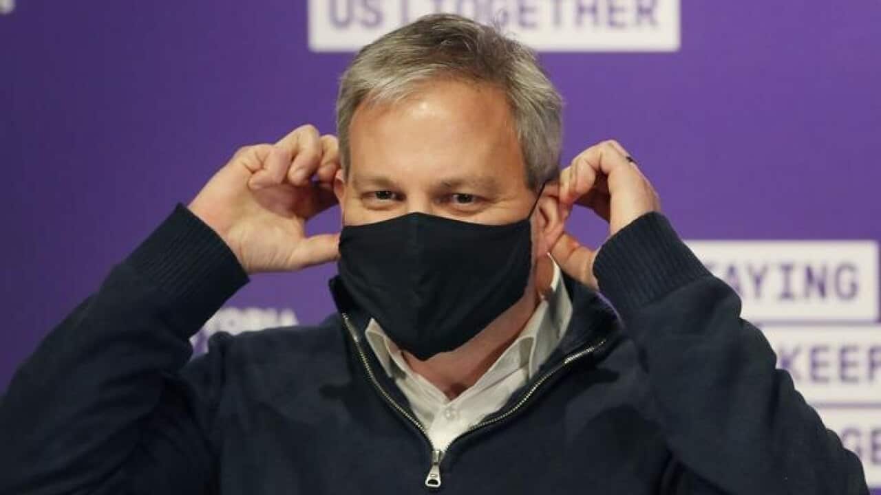 Victorian Chief Health Officer Brett Sutton puts on a mask while he speaks to the media during a press conference in Melbourne