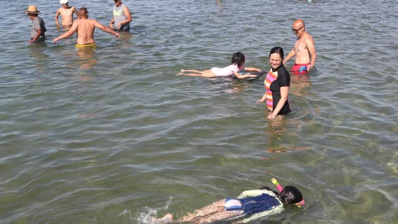 People are seen in the water at Altona beach in Melbourne.
