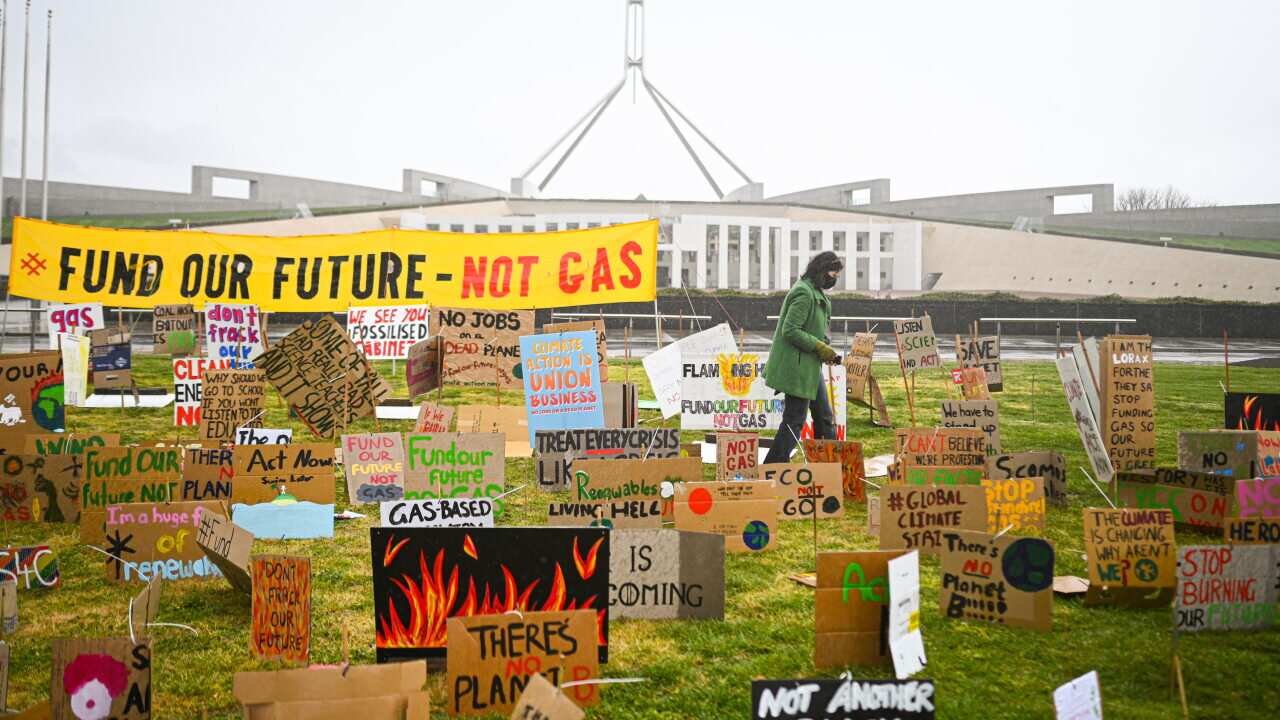 A school student walks amongst signs during a student climate protest outside Parliament House in Canberra, Friday, September 25, 2020. (AAP Image/Lukas Coch) NO ARCHIVING