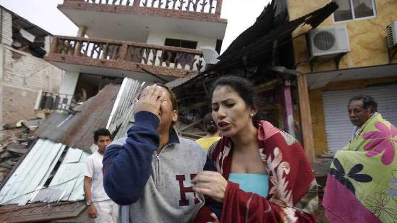 A woman cries as she stands next to house destroyed by the earthquake in the Pacific coastal town of Pedernales, Ecuador, Sunday, April 17, 2016. (AAP)