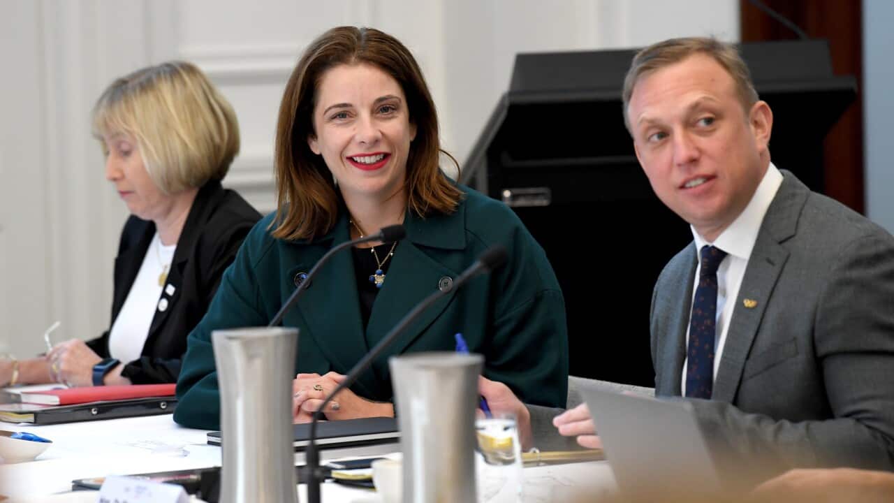 Anika Wells sitting at a table with colleagues