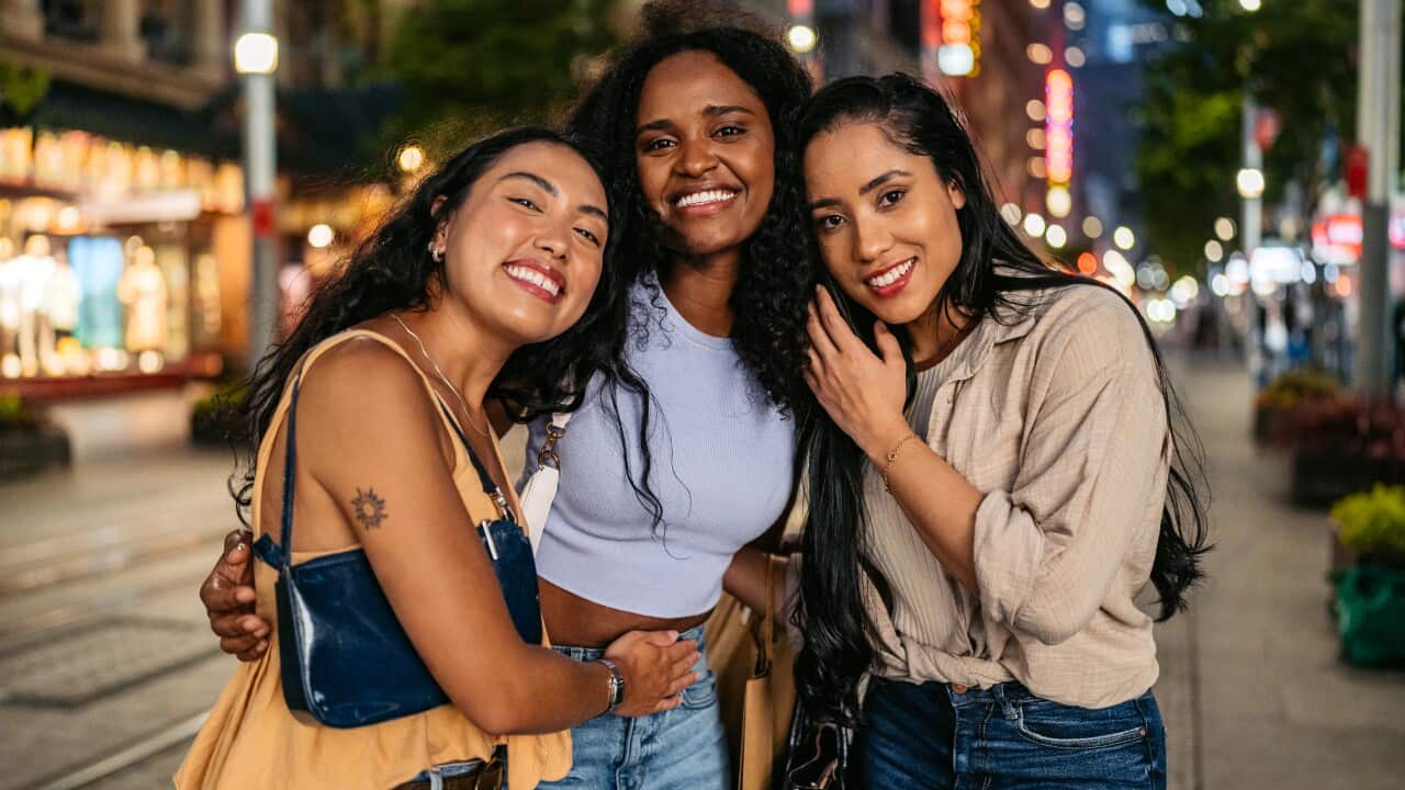 Three Young Female Friends Embracing On The Street In Sydney In Australia At Night