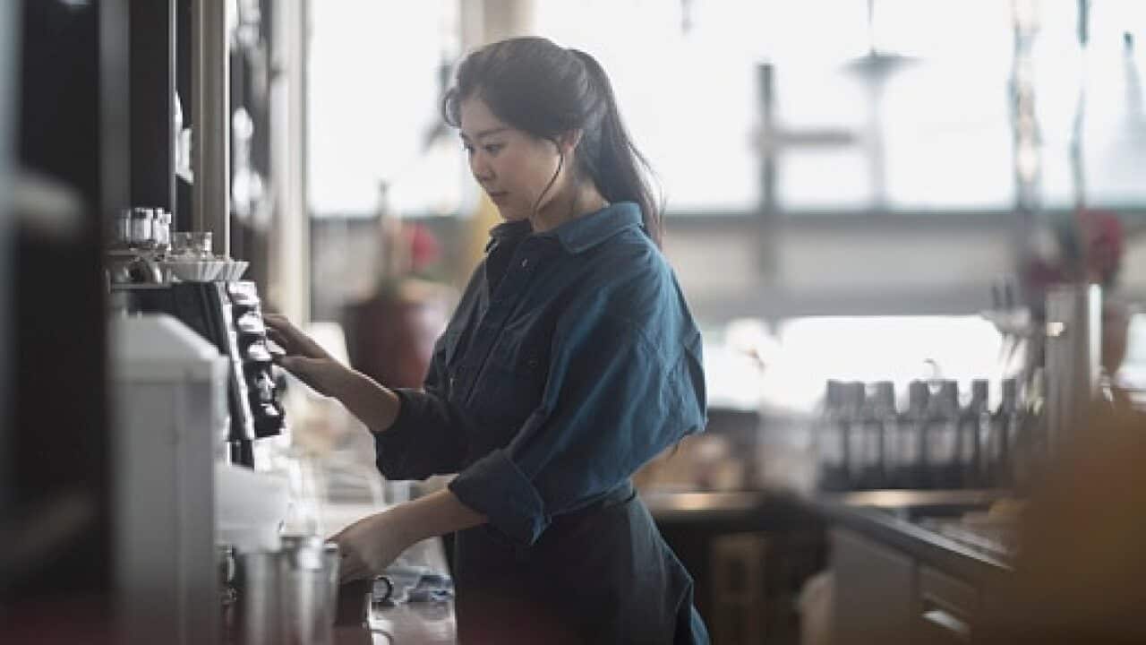 Woman making coffee in cafe