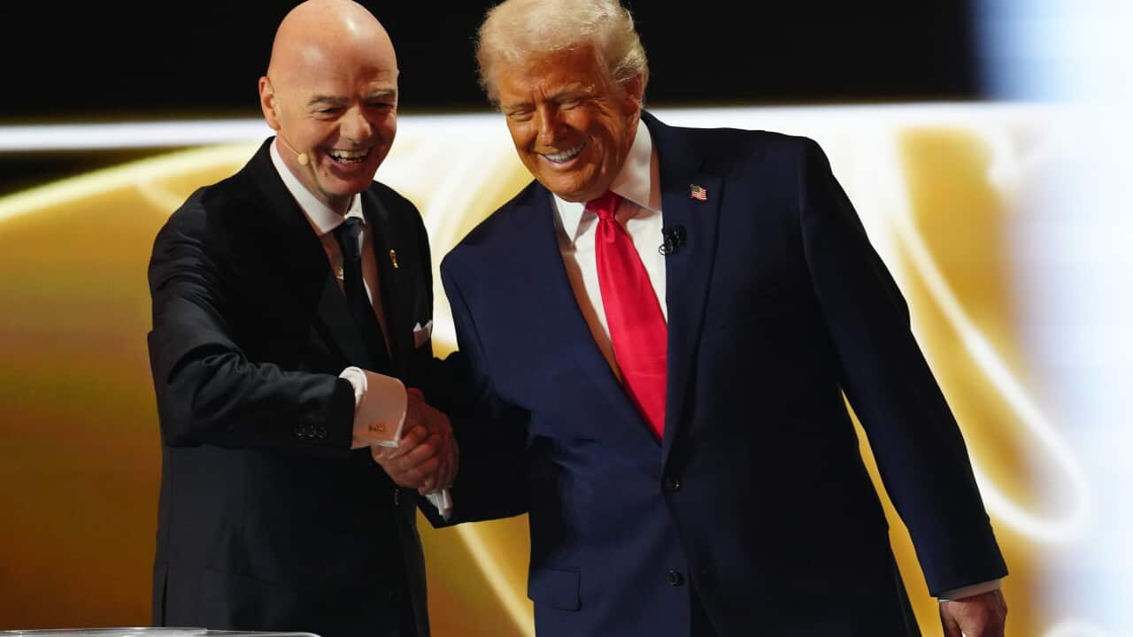 Two white men in dark suits shaking hands and smiling.