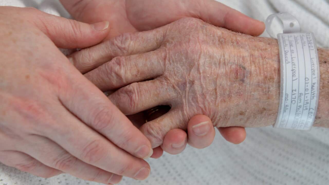 A nurse holds the hand of an elderly patient