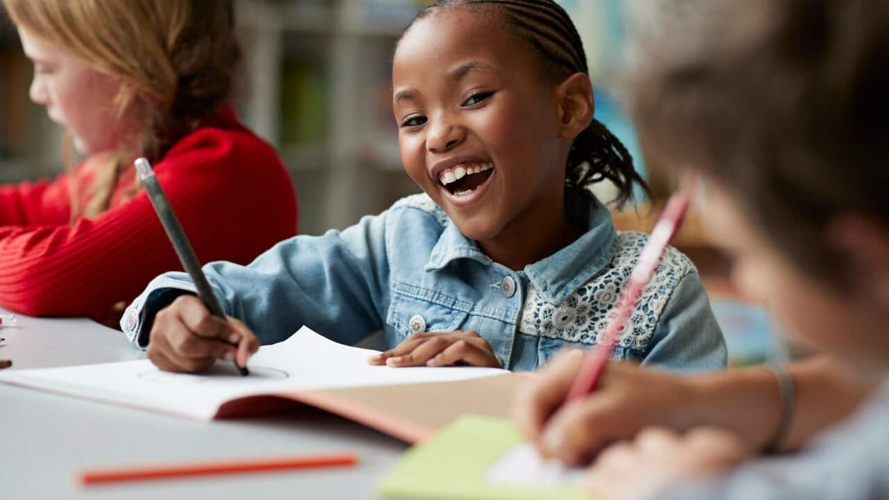 Portrait of schoolgirl drawing at the school library and laughing