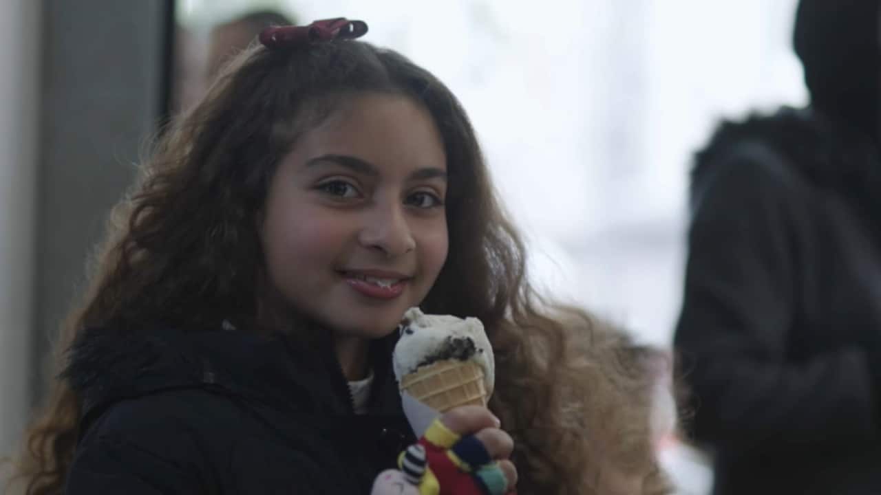 A Palestinian girl is smiling while holding an ice cream in a Gaza cafe