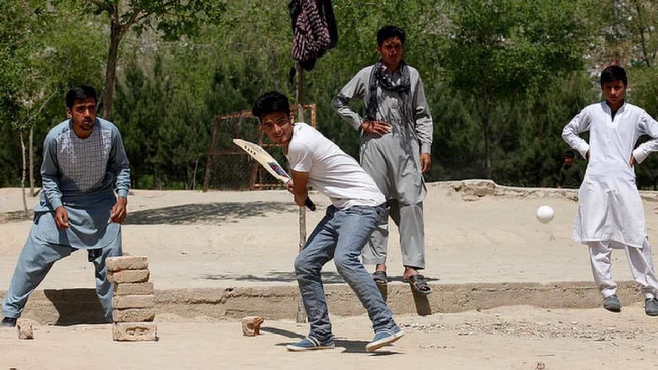 A group of young Afghans playing cricket.
