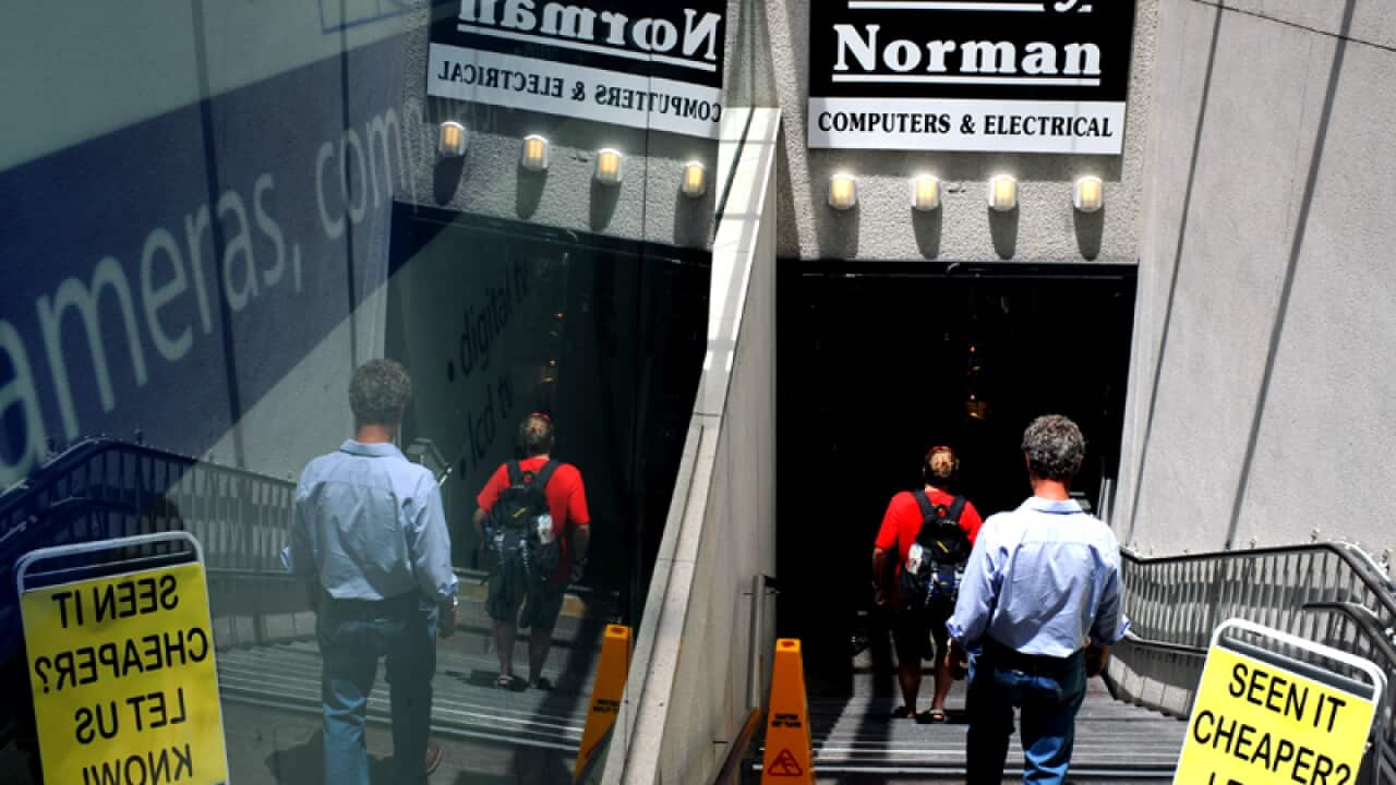 Customers walk down the stairs to enter a Harvey Norman store