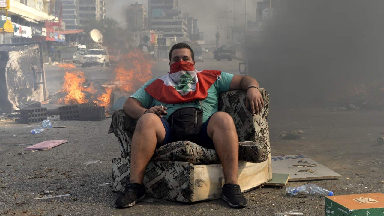 A protester sits in a street to block the Dora highway during a protest in north of Beirut.
