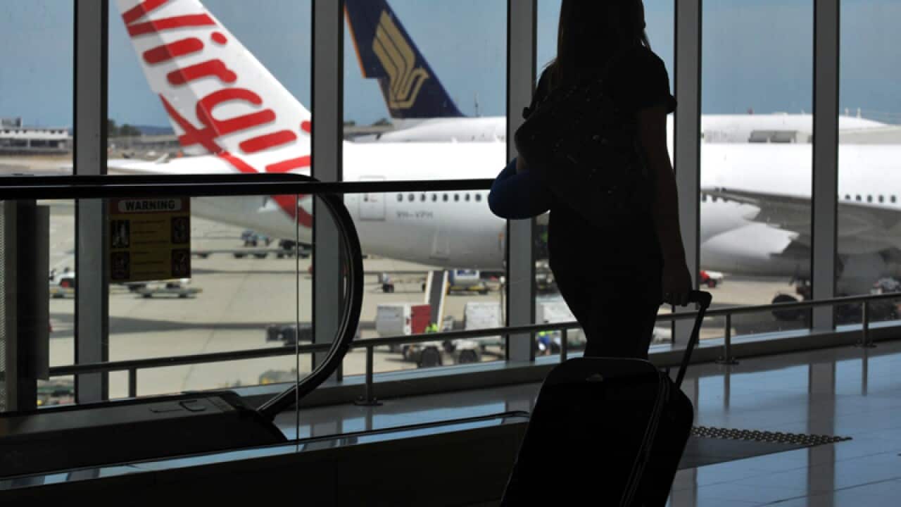 A passenger walks past aircraft at Sydney Airport
