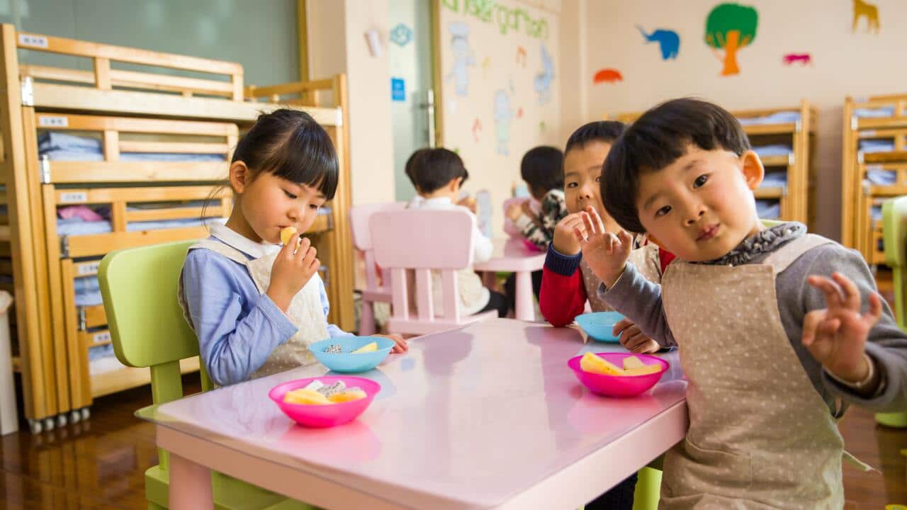 Three toddlers eating on white table
