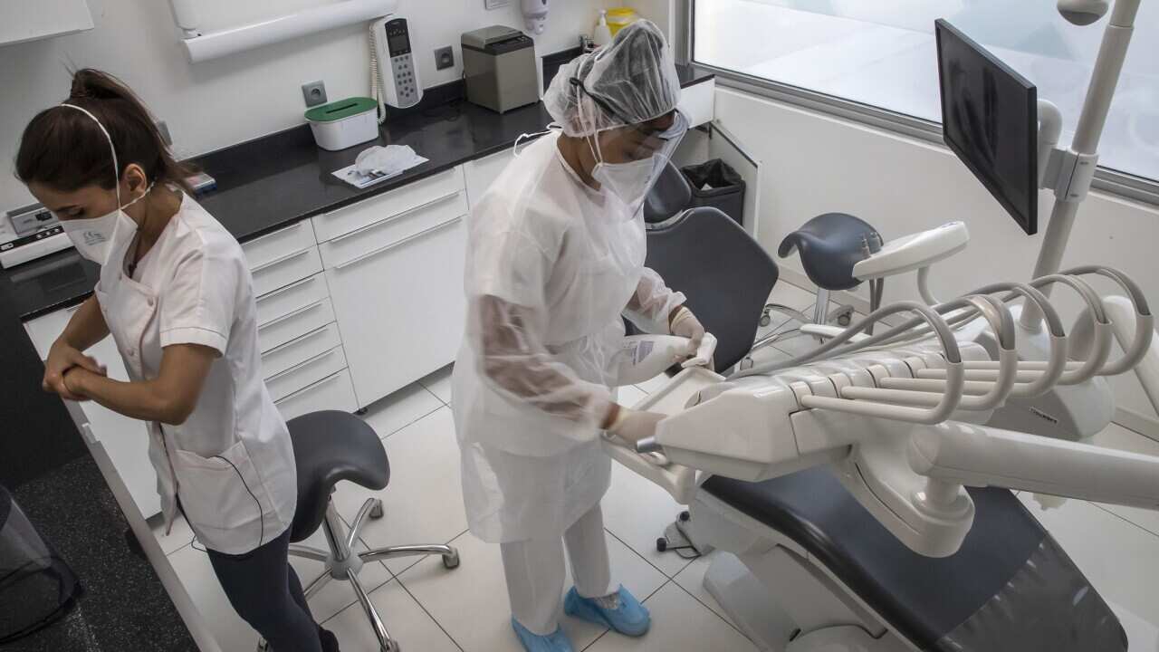 A dentist and her assistant prepare for a dental appointment