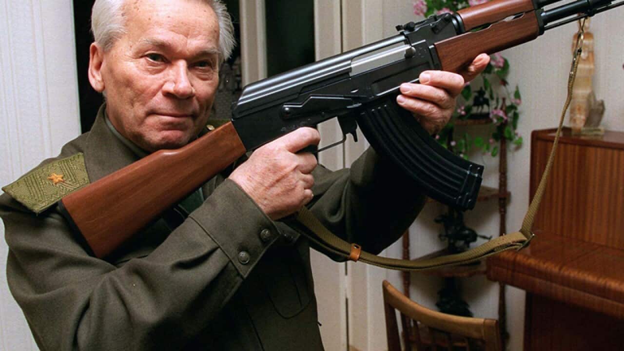 Mikhail Kalashnikov holding an AK-47 assault rifle
