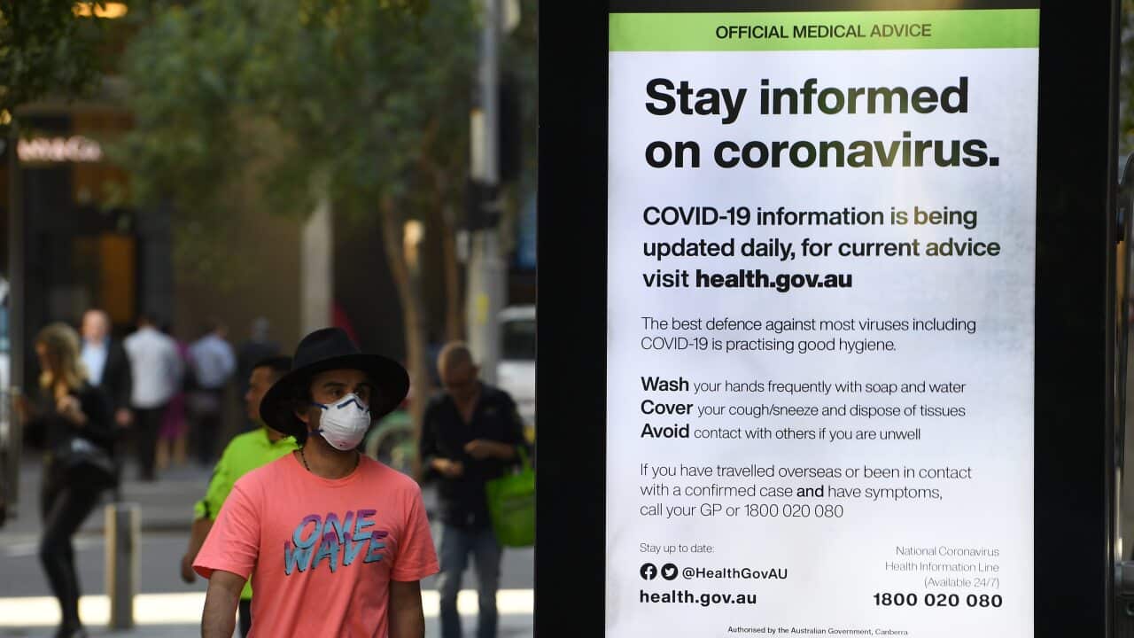 A man wearing a protective mask walks past an official medical advice advertisement in Sydney's Pitt Street Mall.