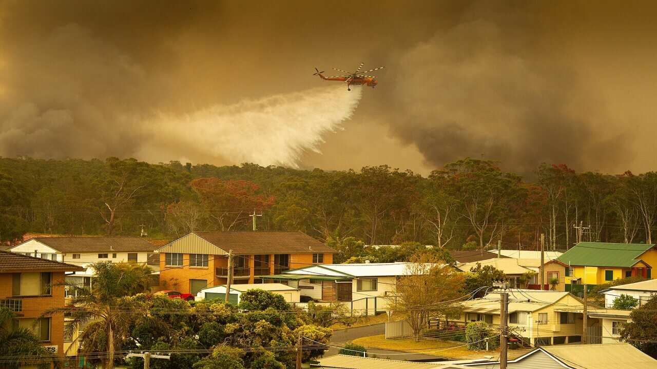 An Aircrane water bombing helicopter drops water on a bushfires in Harrington, 335km north east of Sydney, Friday, November 8, 2019. Hot, windy conditions are wreaking havoc as bushfires burn out of control across parts of NSW, with 15 current emergency w