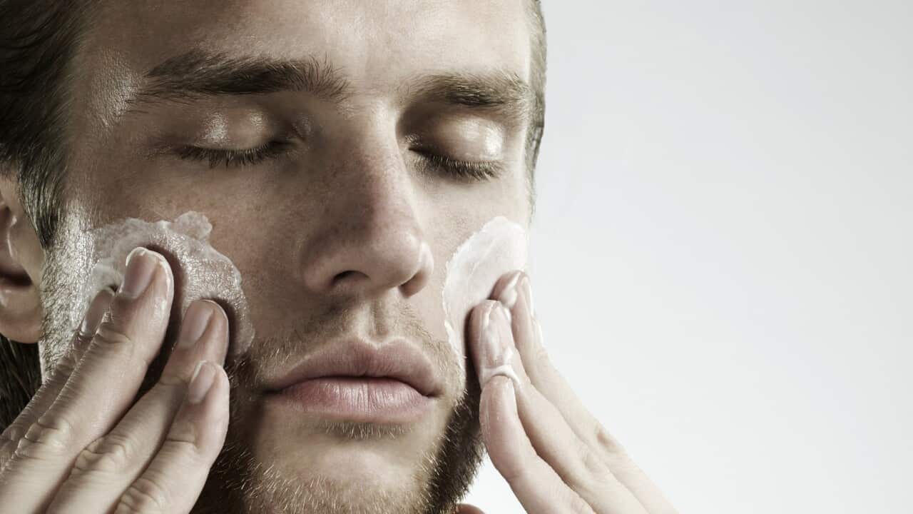 portrait of man applying moisturizer to face