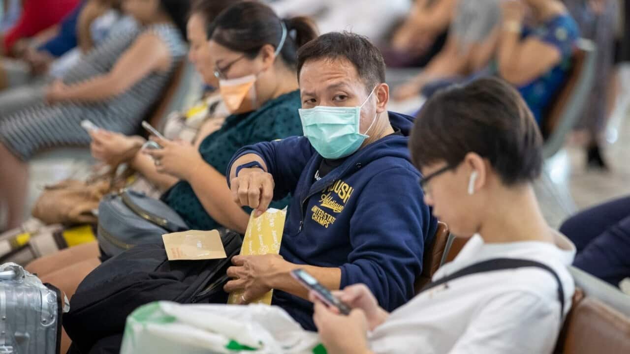 People wearing protective face masks to protect themselves from Coronavirus are seen at Brisbane International Airport