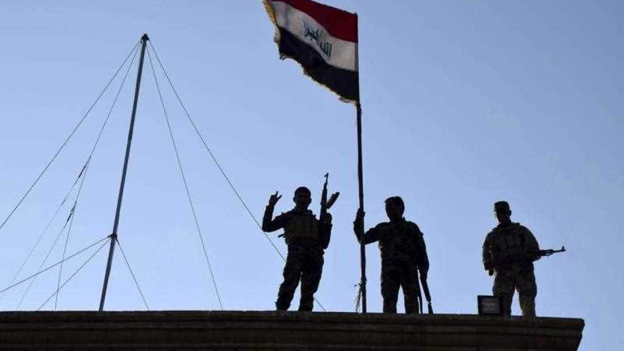 Iraqi soldiers plant the national flag over a government building in Ramadi as security forces advance their position in northern Ramadi, 70 miles (115 kilometers) west of Baghdad, Iraq.