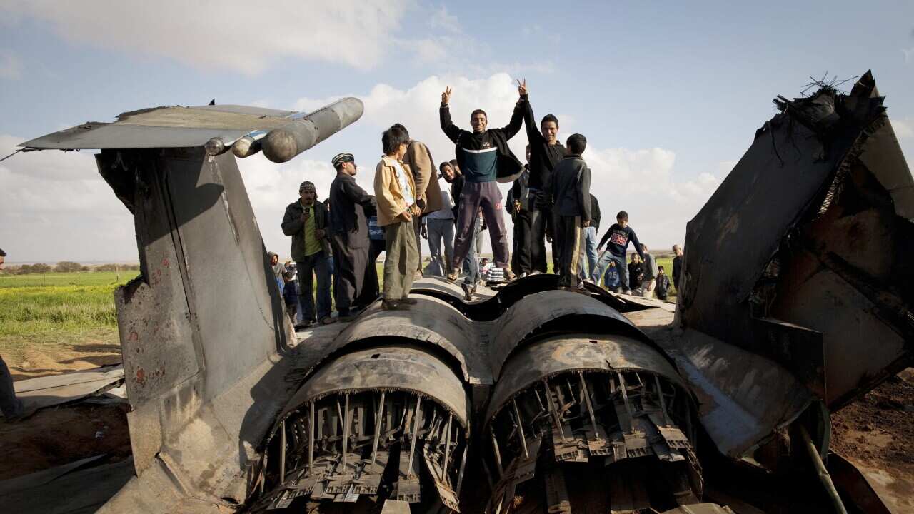 Libyans pose on the wreckage of a US F15 fighter jet after it crashed in an open field in the village of Bu Mariem. (AAP)