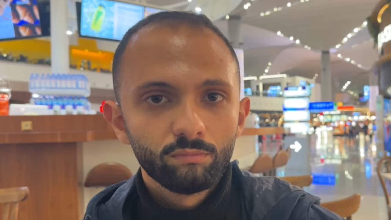 A man with a beard sitting in an airport food court