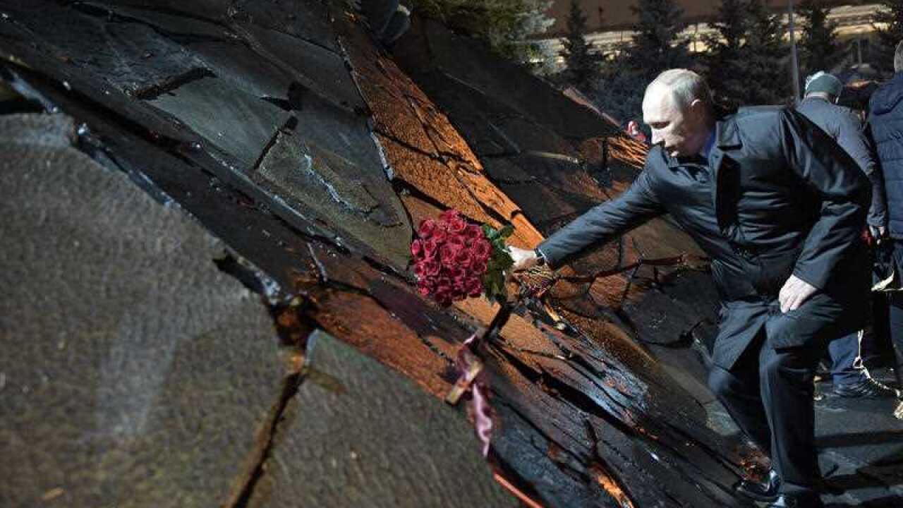 Russian President Vladimir Putin, lays a bunch of flowers as he he attends a ceremony unveiling the country's first national memorial to victims of Soviet-era political repressions called "The Wall of Grief" in Moscow, Russia, Monday, Oct. 30, 2017.