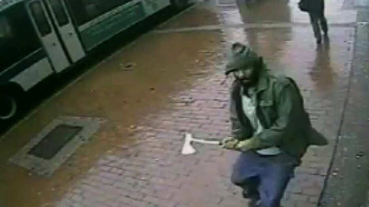 A man approaches New York City police officers with a hatchet