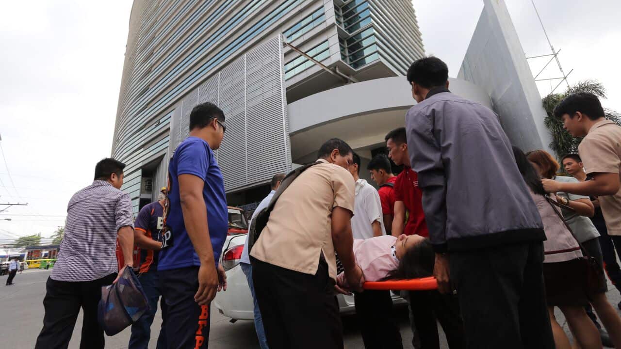 An office worker is carried on a stretcher after she fainted at the height of the earthquake that hit Davao City, in southern island of Mindanao.
