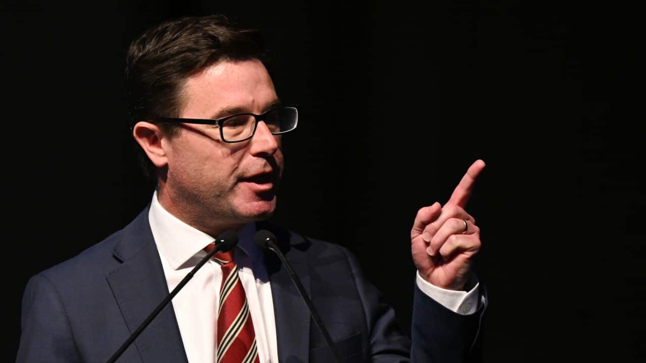 A man with glasses raises his index finger as he speaks.