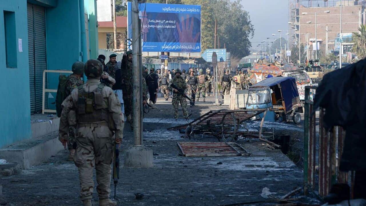 Afghan security personnel keep watch along a street after an attack from a building close to the Pakistan consulate in Jalalabad.